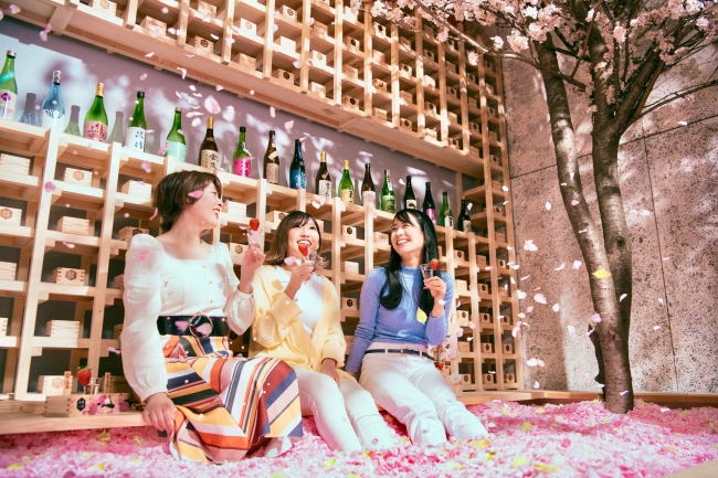 桜の木が配置された室内でお花見を楽しむ3人の女性